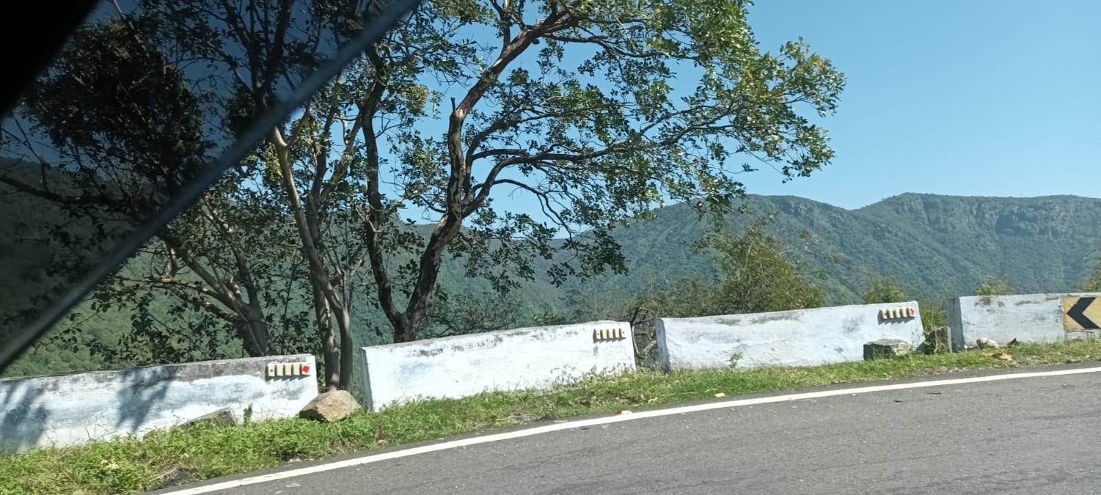 Scenic mountain viewpoint along a ghat road with crash barriers in the foreground