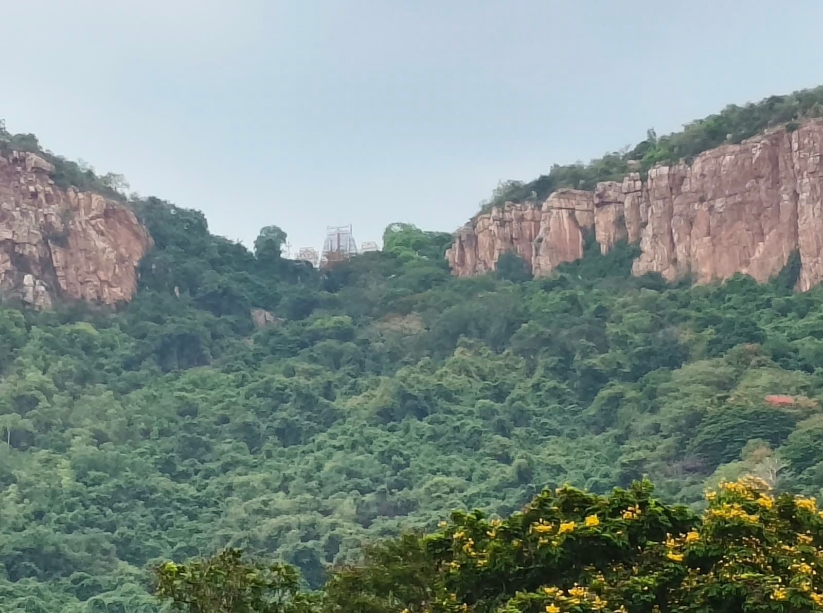 A distant temple gopuram framed between the rocky hills of Tirupati