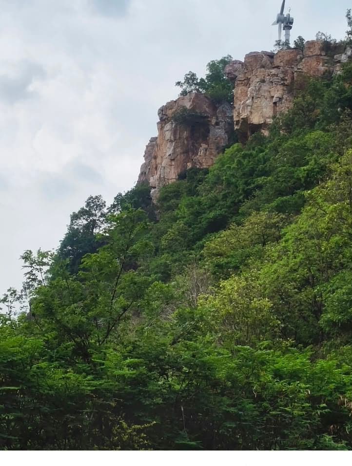 A rocky hilltop cliff near Tirupati with a wind turbine on the ridge